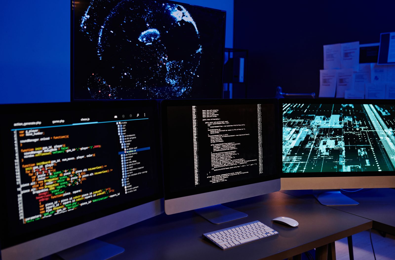 Monitors full of code in a dark office