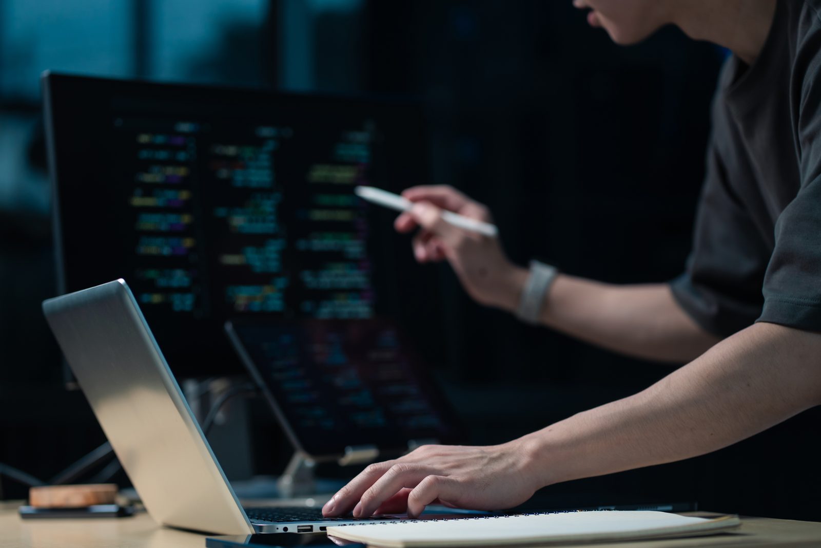 Developer working with multiple screens and laptop