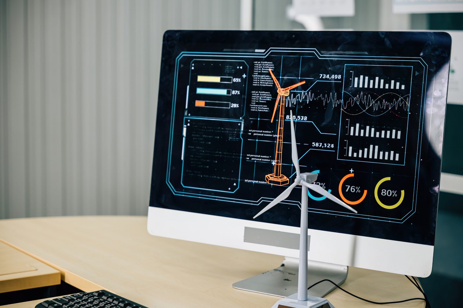 A model wind turbine in front of a monitor showing energy data